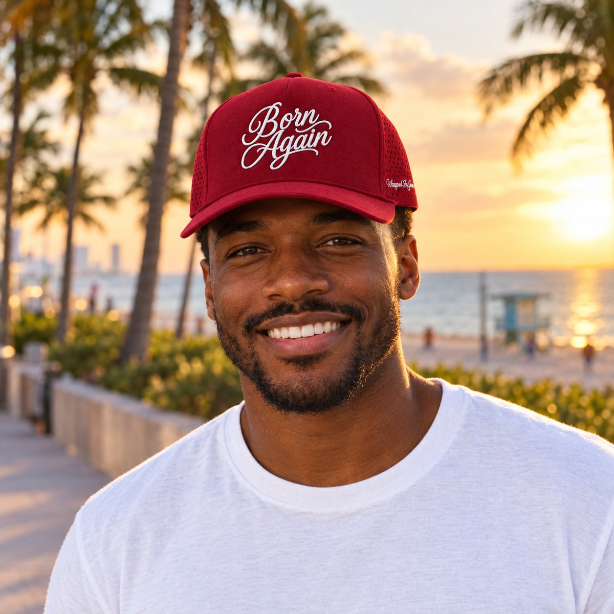 Man wearing red Born Again Christian performance hat on a Miami Beach boardwalk at sunset