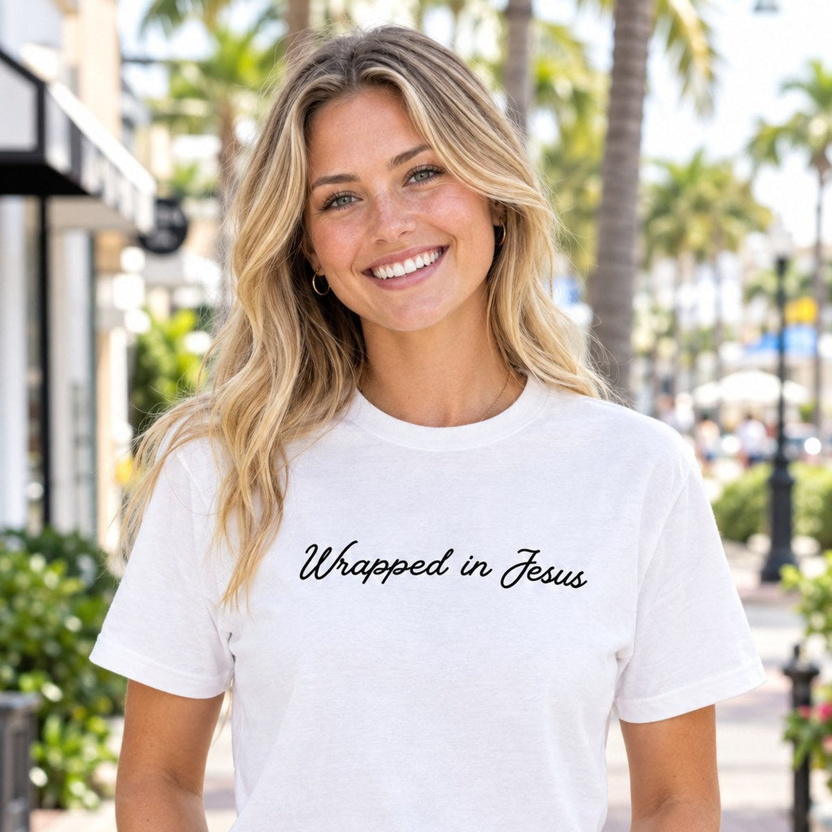 Woman wearing white Wrapped In Jesus script Angel tee on a Delray Beach sidewalk