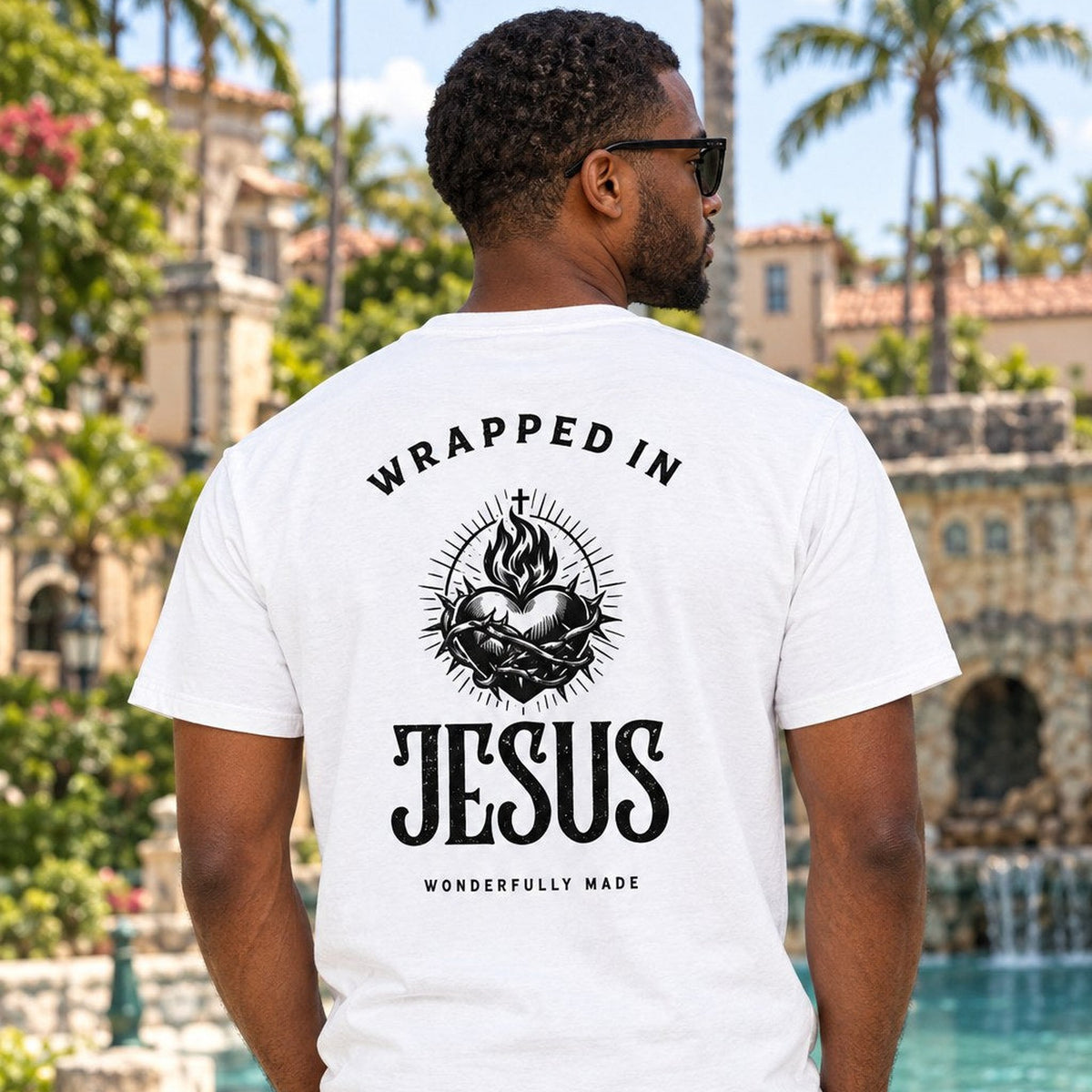 Man wearing white Sacred Heart Wrapped In Jesus tee on a Coral Gables street, back graphic view